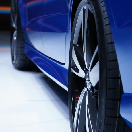 Close-up shot of a blue car highlighting the stylish alloy wheel. Perfect for automotive enthusiasts.